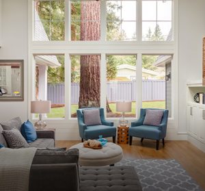 Beautiful living room interior with tall vaulted ceiling, loft area, hardwood floors and fireplace in new luxury home. Has large bank of windows